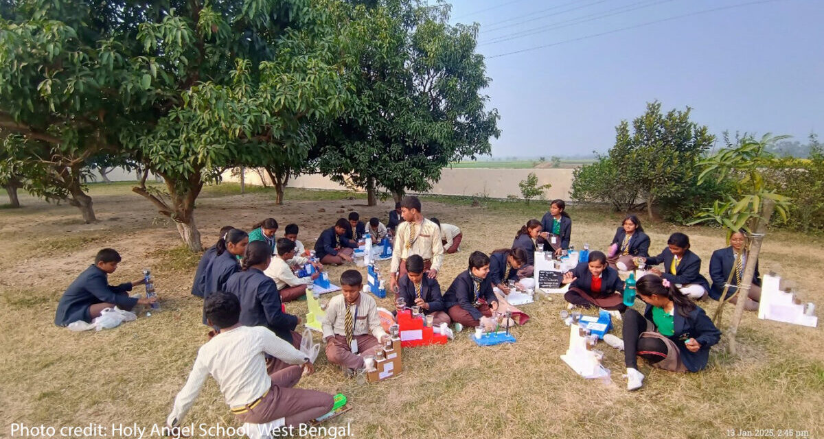 Children sit outside doing an interactive class.
