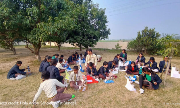 Children sit outside doing an interactive class.
