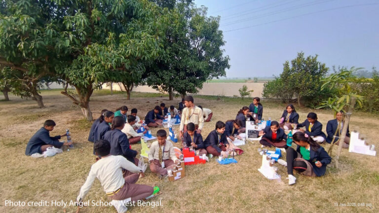 Children sit outside doing an interactive class.