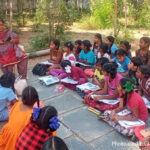 students sit on the floor for their outside classroom, India.