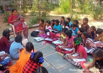 students sit on the floor for their outside classroom, India.