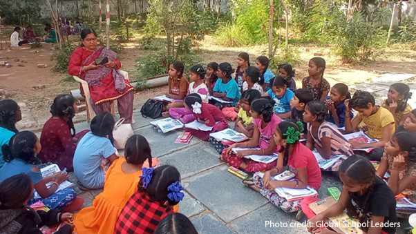 students sit on the floor for their outside classroom, India.