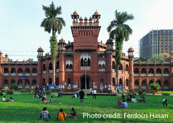 Students sit outside on the grass on a university campus.