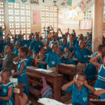 A group of schoolchildren energetically participating in a classroom activity indoors.