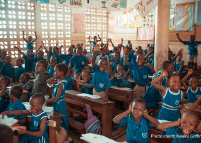 A group of schoolchildren energetically participating in a classroom activity indoors.