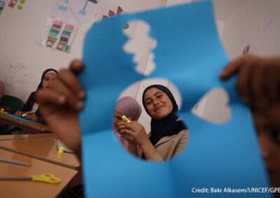 A girl, Hayat, smiles through a cut-out paper shape during a psychosocial activity at a non-formal education centre in Latakia, Syria.