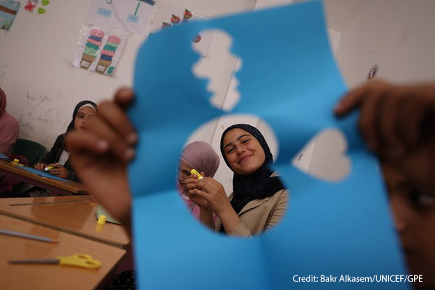 A girl, Hayat, smiles through a cut-out paper shape during a psychosocial activity at a non-formal education centre in Latakia, Syria.