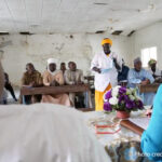 Woman speaking to a room full of people seated around desks