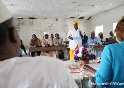 Woman speaking to a room full of people seated around desks