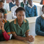 Students sit at desks in class, Zambia.