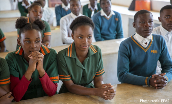 Students sit at desks in class, Zambia.