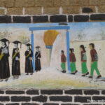 Painting on a school wall of students walking into a school and coming out as accomplished graduates.