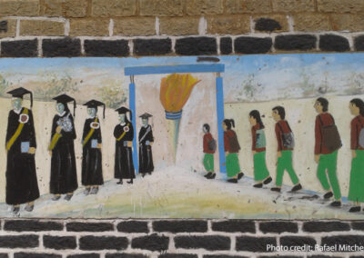 Painting on a school wall of students walking into a school and coming out as accomplished graduates.