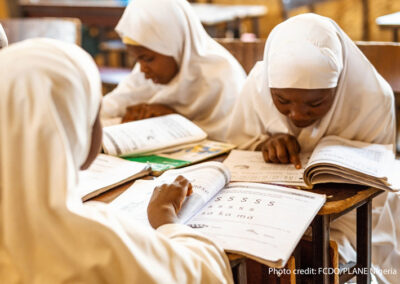 Girls sit looking at textbooks in a classroom in Nigeria.