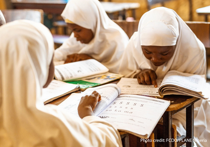 Transforming Educational learning Girls sit looking at textbooks in a classroom in Nigeria.