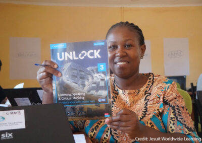 A GEL facilitator at a learning centre at Kakuma Refugee Camp in Kenya holding a Cambridge coursebook