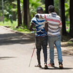 Two men walking together - Peer support from a fellow student for a visually impaired student, Oromia, Ethiopia