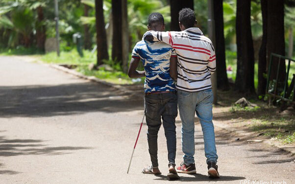 Two men walking together - Peer support from a fellow student for a visually impaired student, Oromia, Ethiopia