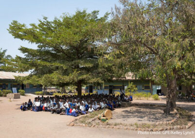 Primary school students wait for their class to start in the shade of a tree, Tanzania.