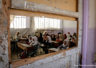 Children sit in a destroyed classroom, Syria. Viewed through an broken window
