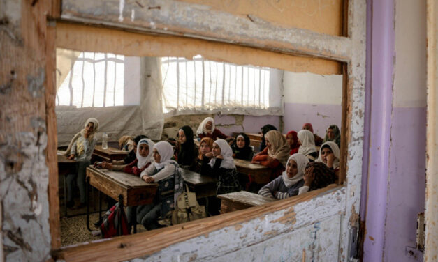 Children sit in a destroyed classroom, Syria. Viewed through an broken window