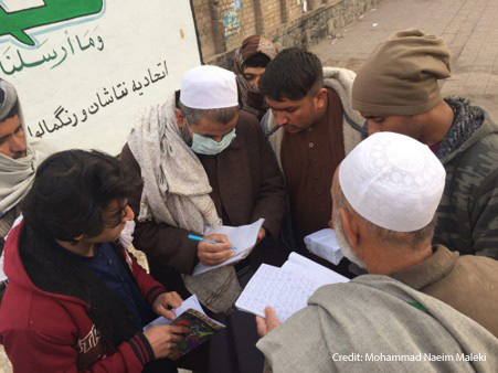 An adult literacy facilitator providing homework for adult learners on the pavement